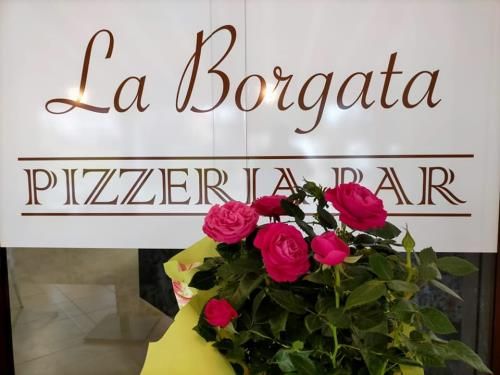 L’insegna La Borgata Pizzeria Bar con un vaso di rose